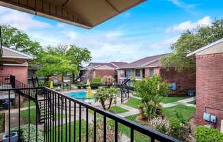 A view from a balcony overlooking a pool and apartment buildings.