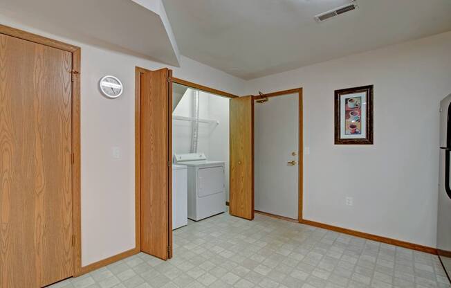 A bright laundry area here at Arbor Ridge featuring in-unit washer and dryer, warm wood trim, and clean flooring. Neutral walls and convenient layout create a practical, welcoming space for everyday living.
