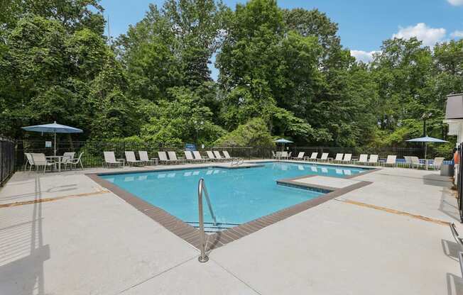 A swimming pool with white lounge chairs around it at Gwinnett Square Apartments in Duluth, GA