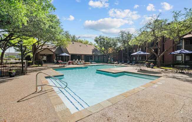 A pool surrounded by trees and a building in the background.