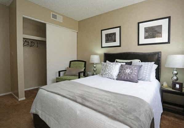 A bedroom with a large bed and a green chair.