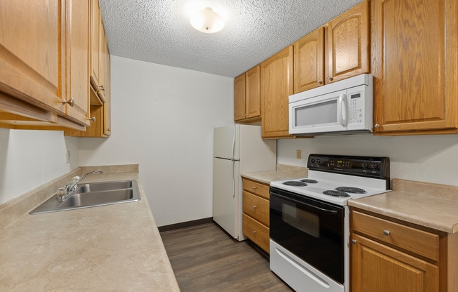 A kitchen with wooden cabinets and white appliances.