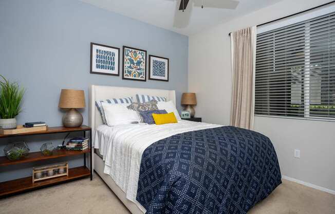 A bedroom with a bed, nightstands, and a plant.