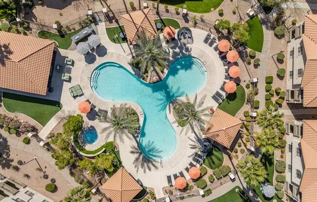 A large swimming pool surrounded by palm trees and orange sun loungers.