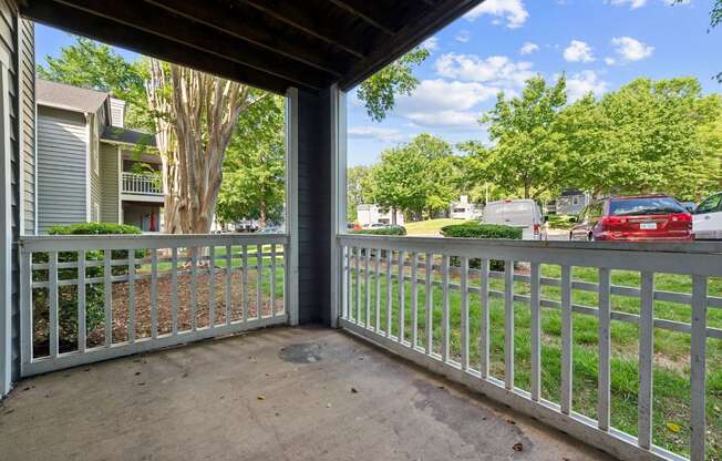 the view from the porch of an apartment building with cars parked in the yard