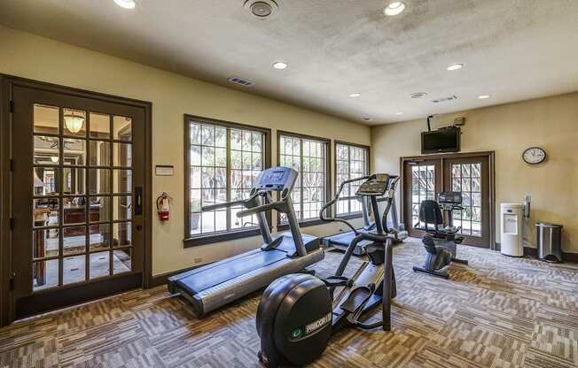 A gym with treadmills, exercise bikes, and a television.