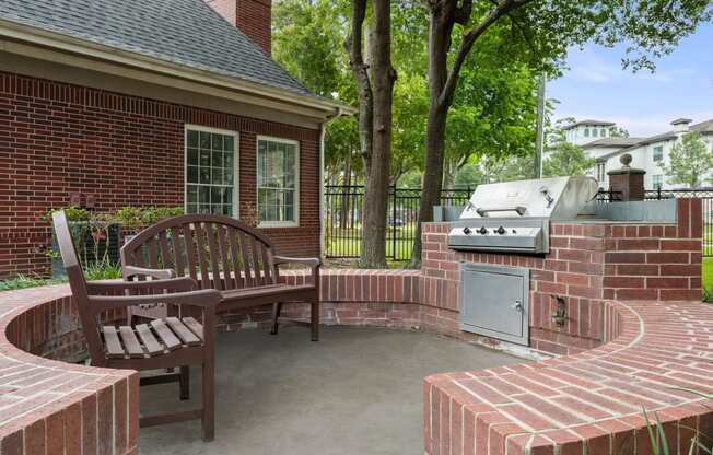 a brick patio with a barbecue grill and a wooden bench at Villages of Cypress Creek, Houston, 77070