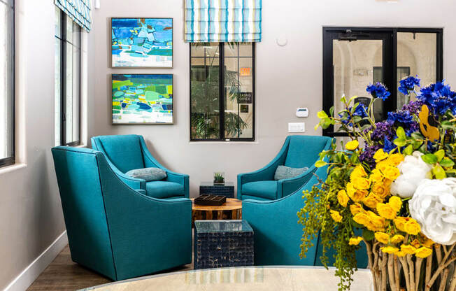 a living room with blue chairs and a vase of flowers