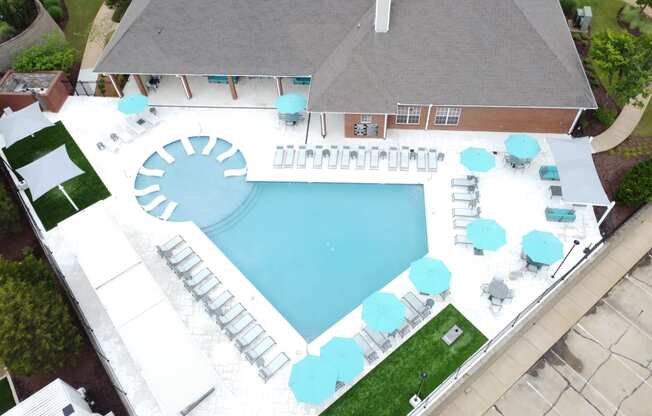 arial view of a swimming pool and patio with umbrellas and a roof