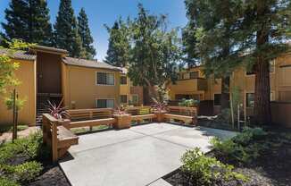a courtyard with benches and trees in front of an apartment building
