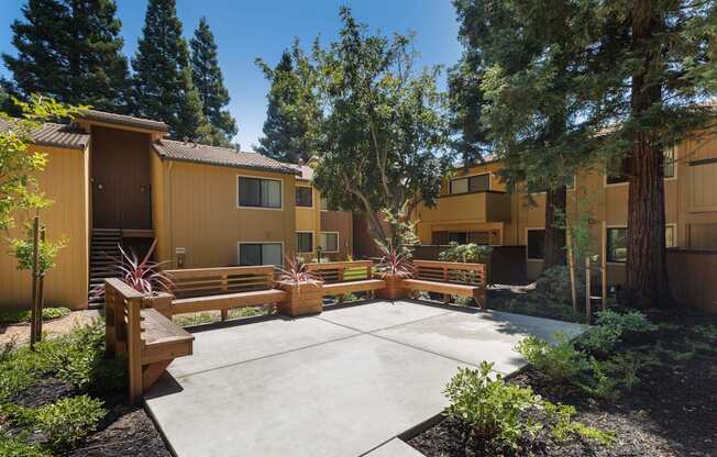 a courtyard with benches and trees in front of an apartment building