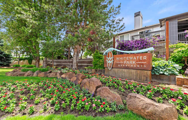 A sign for Whitewater Park Apartments stands in front of a flower bed.