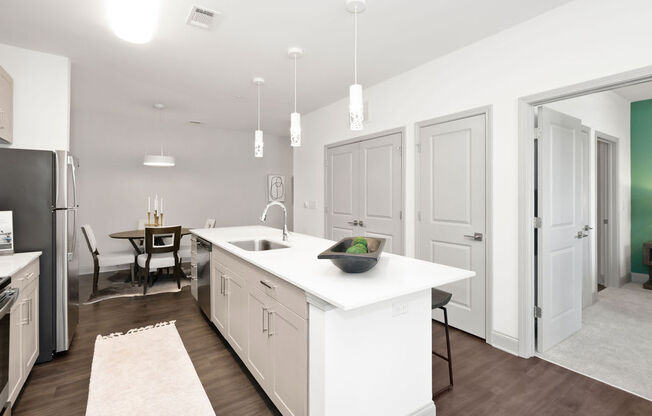 a kitchen with white cabinetry and a large white island with a sink