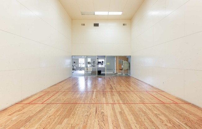 a large room with a racquetball court and a wooden floor
