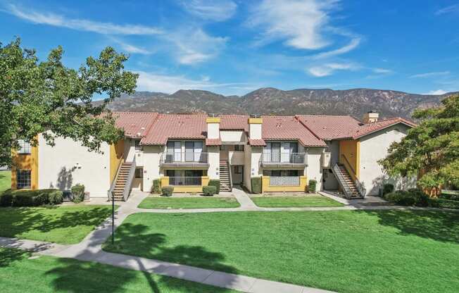 a large house with a lawn and mountains in the background