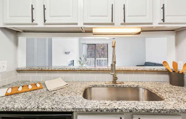 A kitchen with a granite countertop and a stainless steel sink.