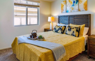 bedroom with nightstands and bed with yellow comforter and pillows at Turtle Creek apartments