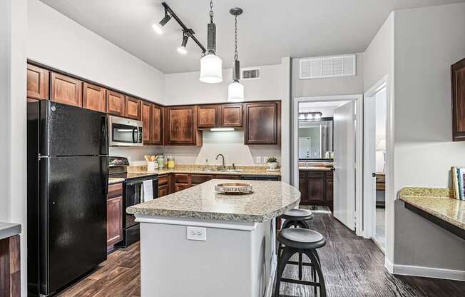 A kitchen with a black fridge and wooden cabinets.