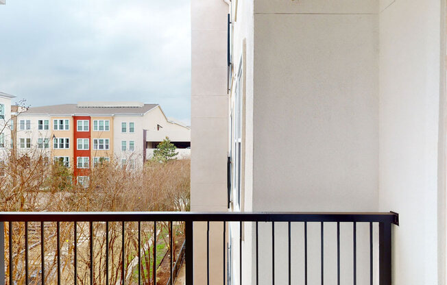 A balcony with a black railing and a white wall.