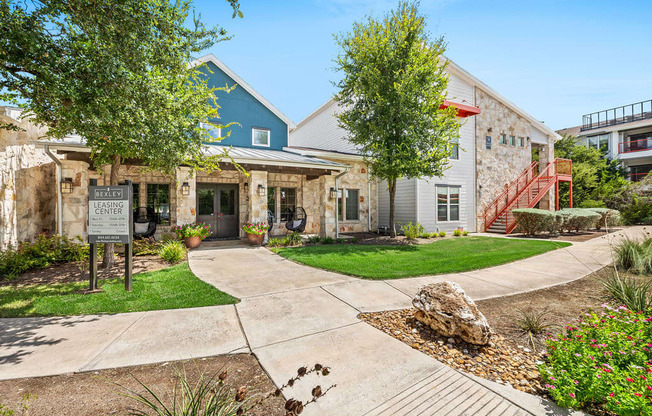 a sidewalk in front of a building with trees and a sign