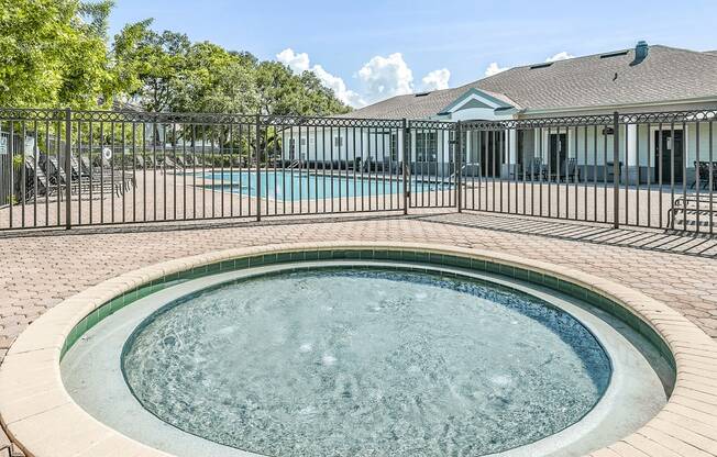 Gated wading pool with swimming pool and deck in background and surrounding native landscape