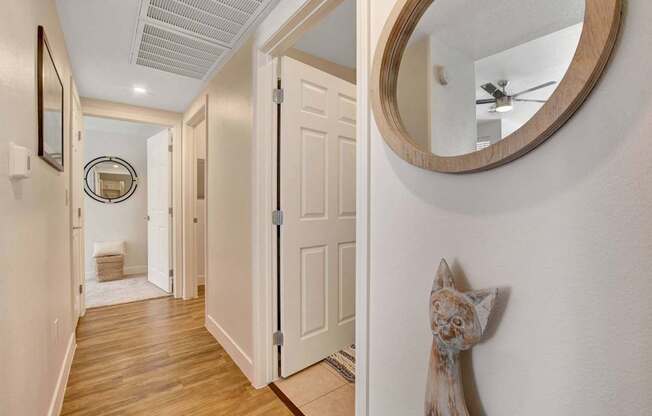 A hallway with a round mirror and a wooden floor.