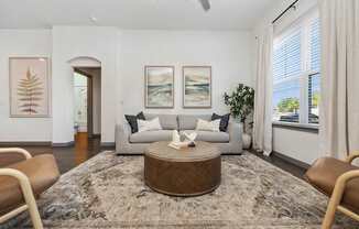 A living room with a brown ottoman and two chairs.