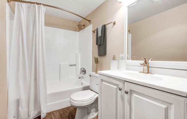 A white bathroom with a toilet, sink, and shower.