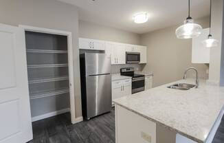 a kitchen with a marble counter top and a stainless steel refrigerator