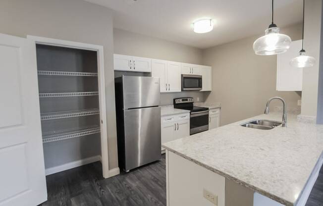 a kitchen with a marble counter top and a stainless steel refrigerator