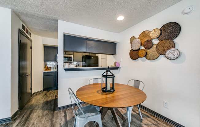 a dining area with a table and chairs and a kitchen in the background