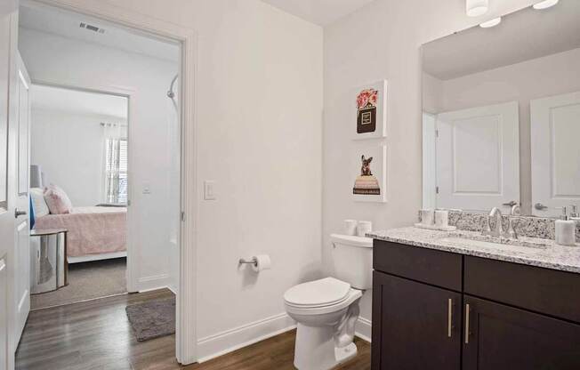 A white toilet sits in a bathroom with a wooden floor and white walls.