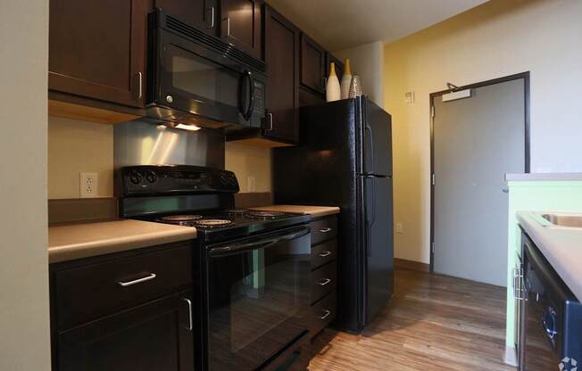 A kitchen with black appliances and wooden floors.
