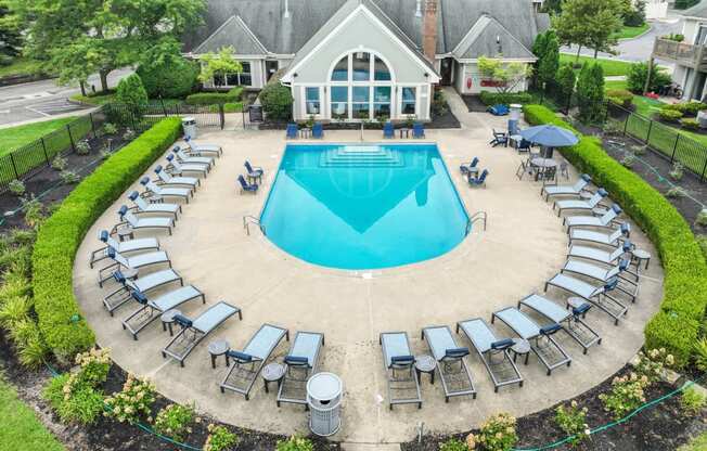 a pool with lounge chairs and umbrellas in front of a house