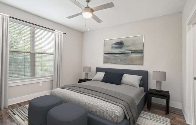 A bedroom with a bed, two ottomans, and a ceiling fan.