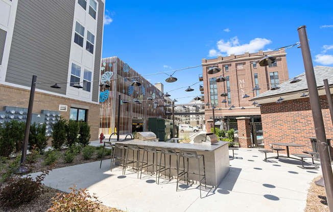 a patio with a bar and chairs in front of a building