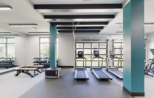 the gym has treadmills and other exercise equipment in a room with windows