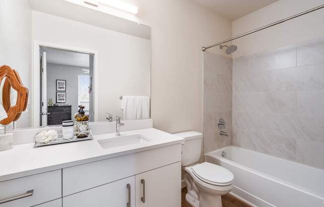 a bathroom with white cabinets and a white toilet next to a white bathtub