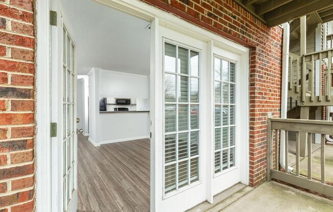 A brick building exterior with an open white door at Ashley Oaks Apartments in Greensboro, NC