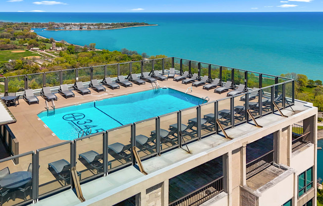 A pool with lounge chairs is surrounded by a balcony railing.