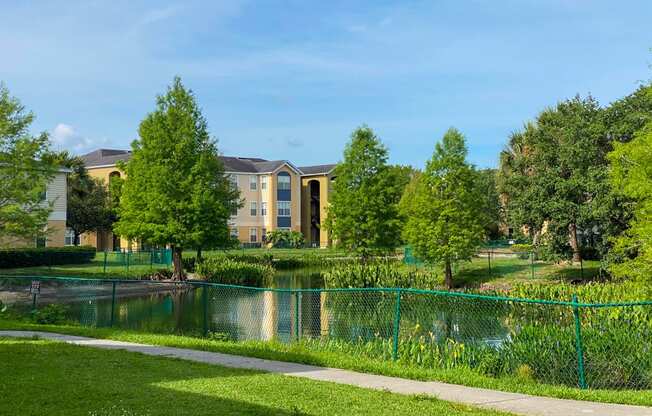 Lake view with a green fence around it and building exteriors in the background