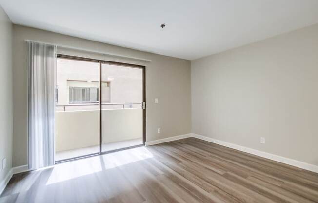 A room with a sliding glass door leading to a balcony.