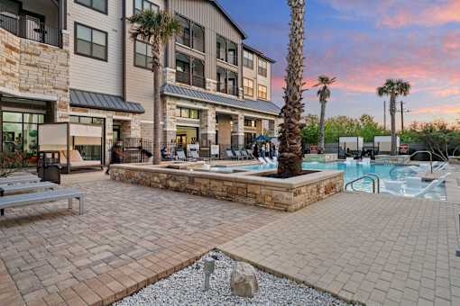 A pool area with a stone bench and a palm tree.