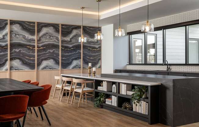 A modern kitchen with a black countertop and red chairs.