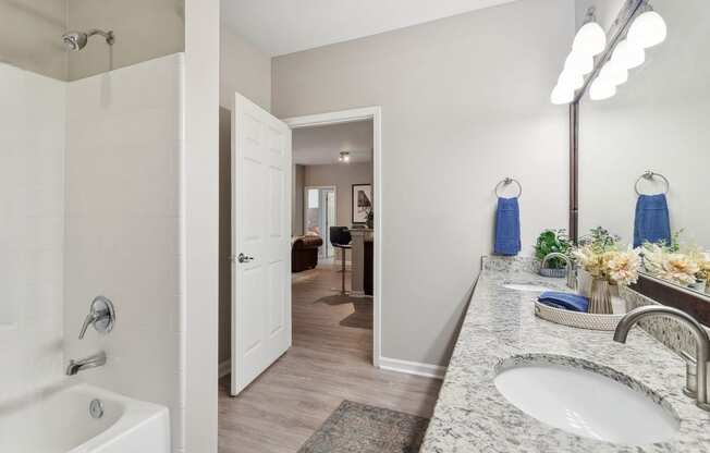 luxury bathroom with tub tile surrounds, granite countertops, and designer lighting at Sorelle apartments