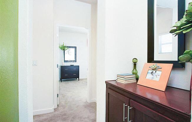 A hallway with a green wall and a brown cabinet with a picture on top.