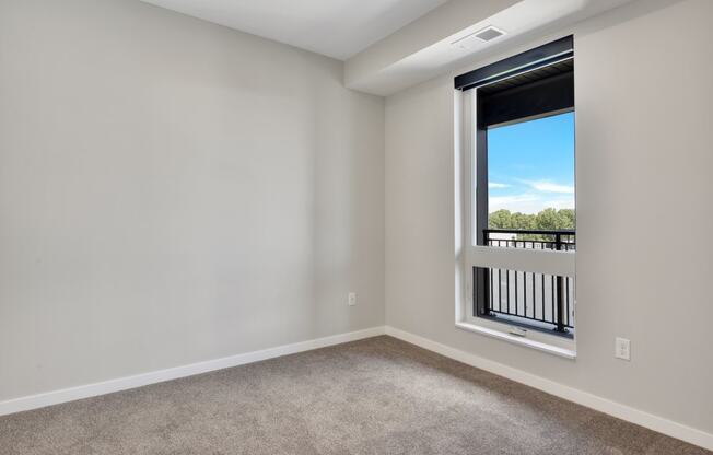 a bedroom with a large window and carpet