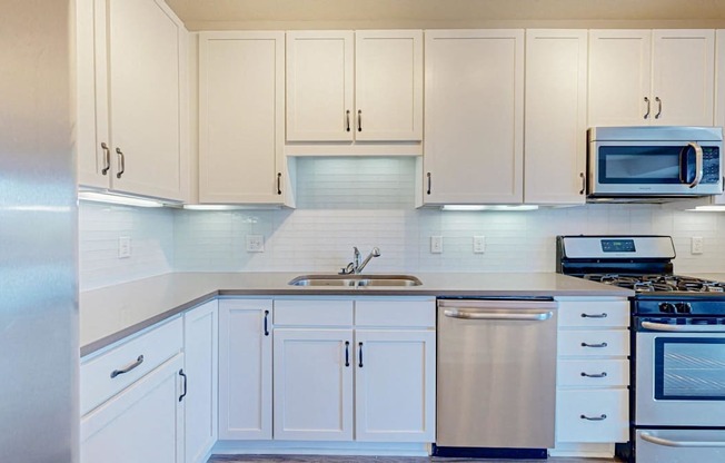 A kitchen with white cabinets and appliances.