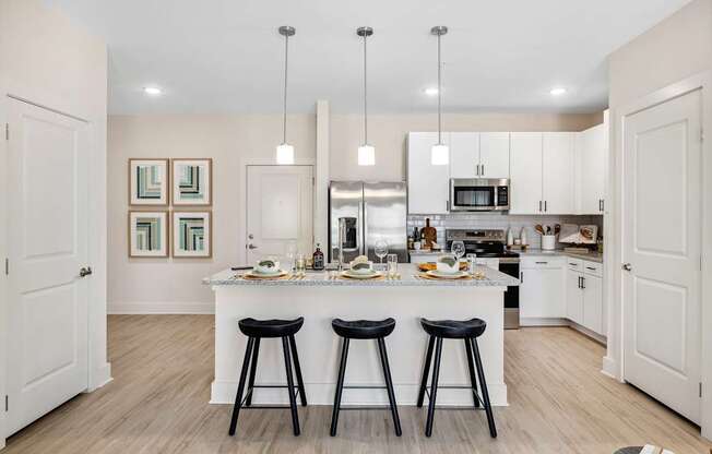 A kitchen with a white island and black stools.