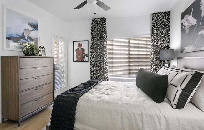 A bedroom with a bed, a dresser, and a ceiling fan.